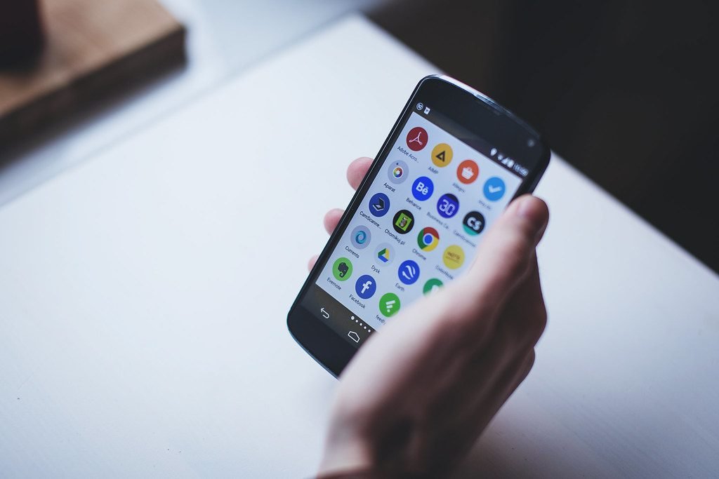 Hand holding an Android phone with apps on screen