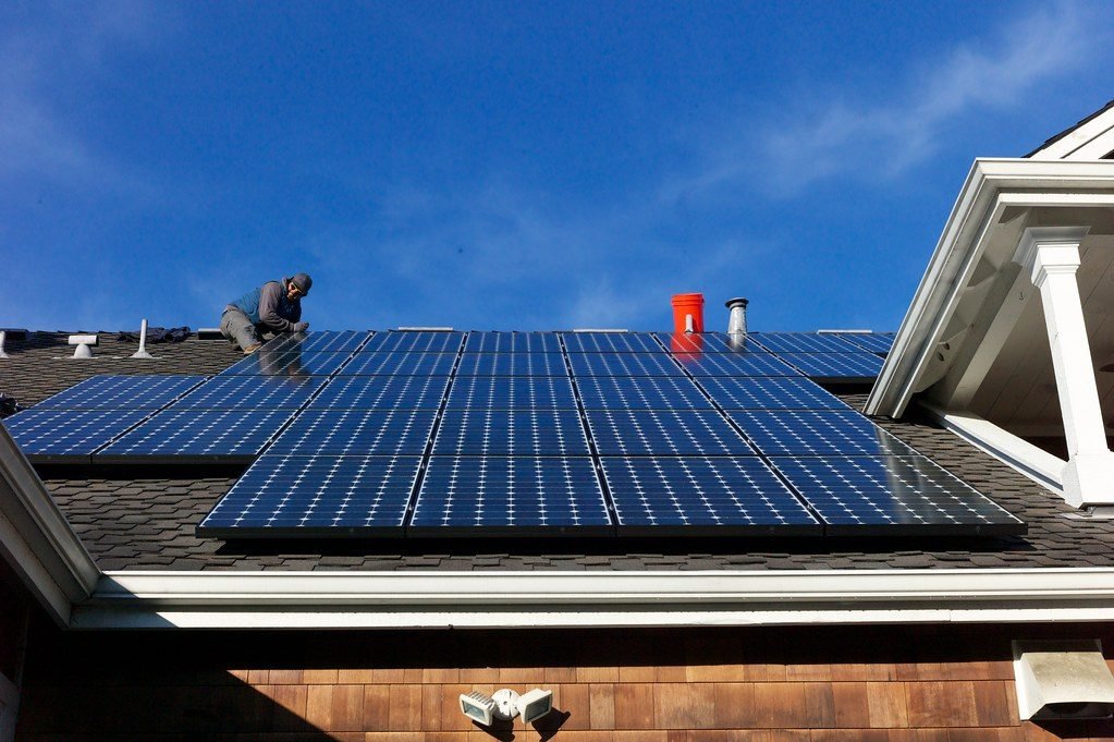 Workers installing a rooftop solar panel array