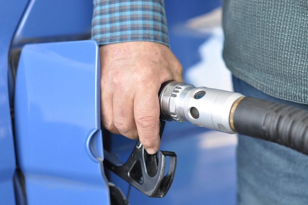 Driver holding fuel nozzle while filling petrol in a car