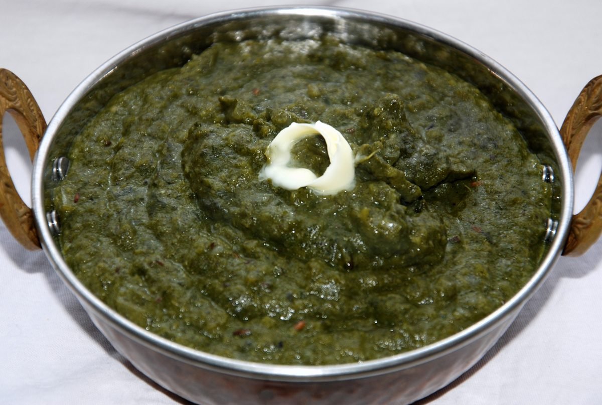 Sarson ka saag topped with white butter in a bowl