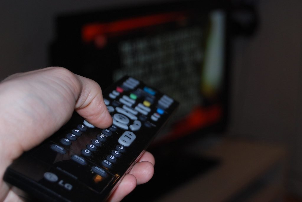 Hand holding TV remote to change drama channel